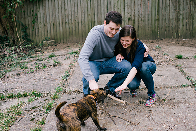 engagement photo of couple playing with their dog at home